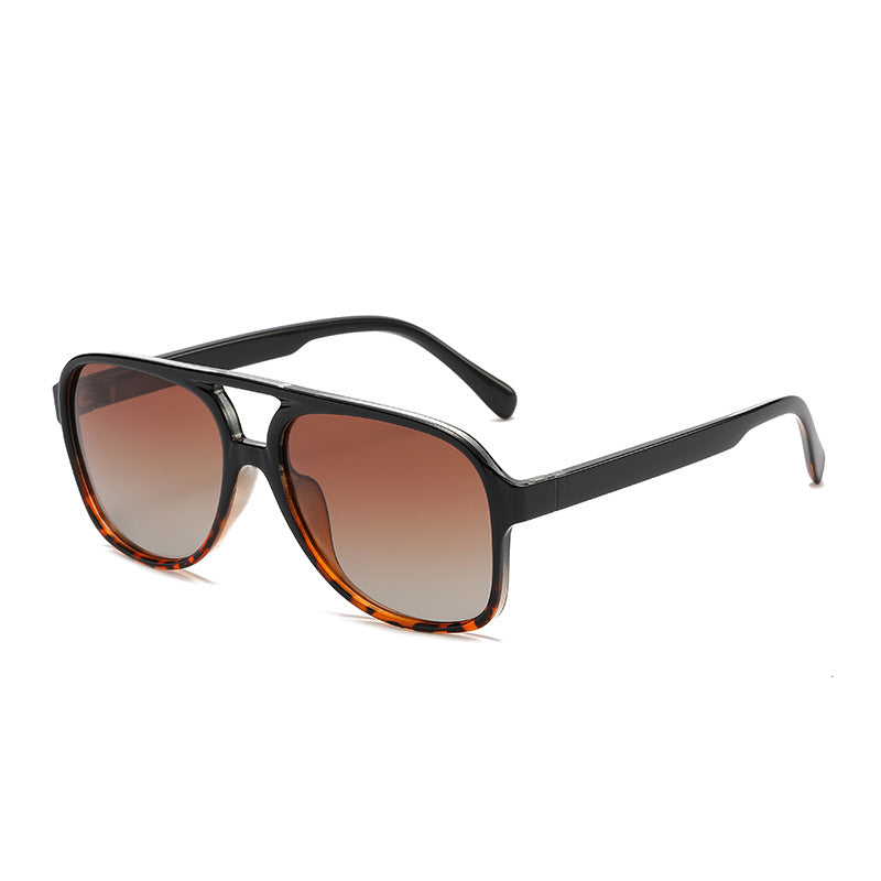 Sunglasses with a black frame and brown gradient lenses on a white background
