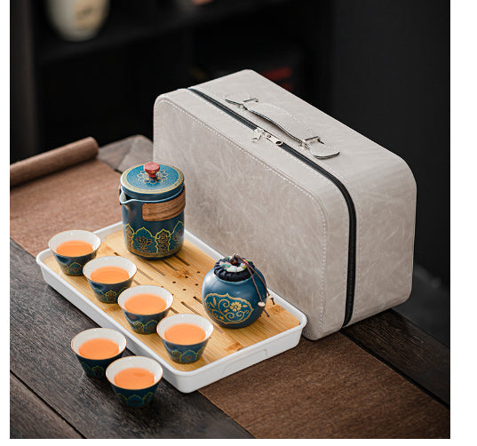 Tea set with teapot and cups on a tray next to a beige travel case.