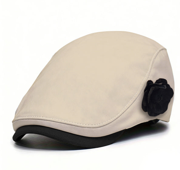 Beige fabric beret with black flower accent and dark brim trim.