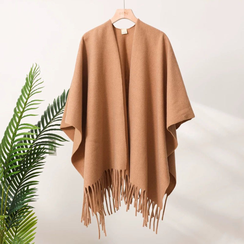 Brown poncho with fringe on a hanger against a white background