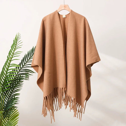 Brown poncho with fringe on a hanger against a white background