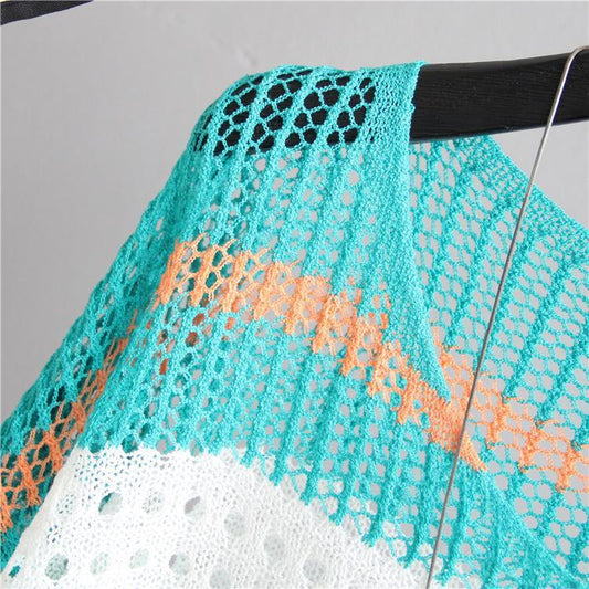 Knitted shawl with a geometric pattern on a hanger against a gray background