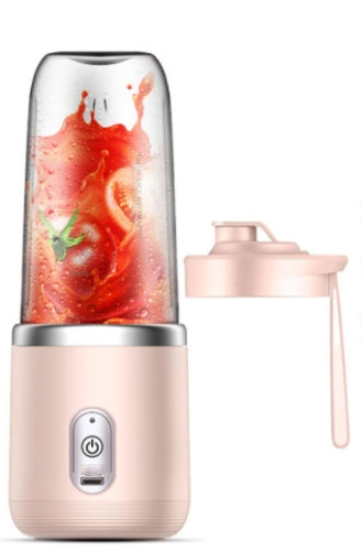 Personal blender with a pink base and clear container filled with a red liquid and green leafy vegetables on a white background.