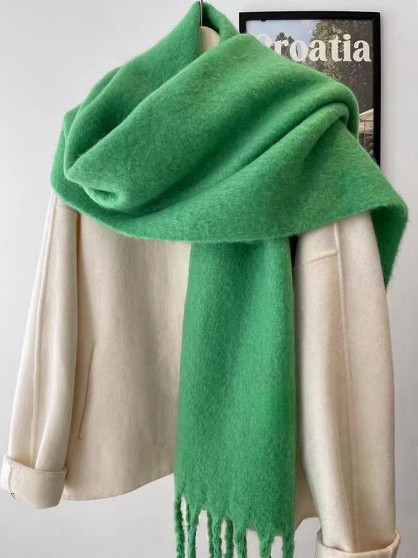 Green scarf draped over a beige coat on a white background