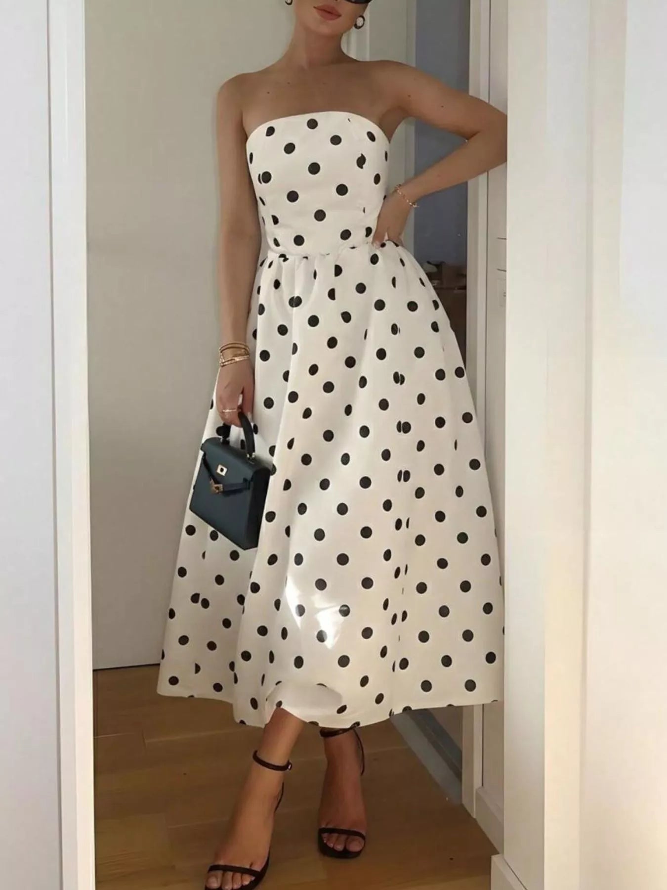 Woman wearing a strapless polka dot dress in a room.