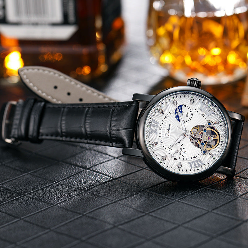 Luxury watch with black leather strap on a textured surface, with blurred background of bottles and glasses.