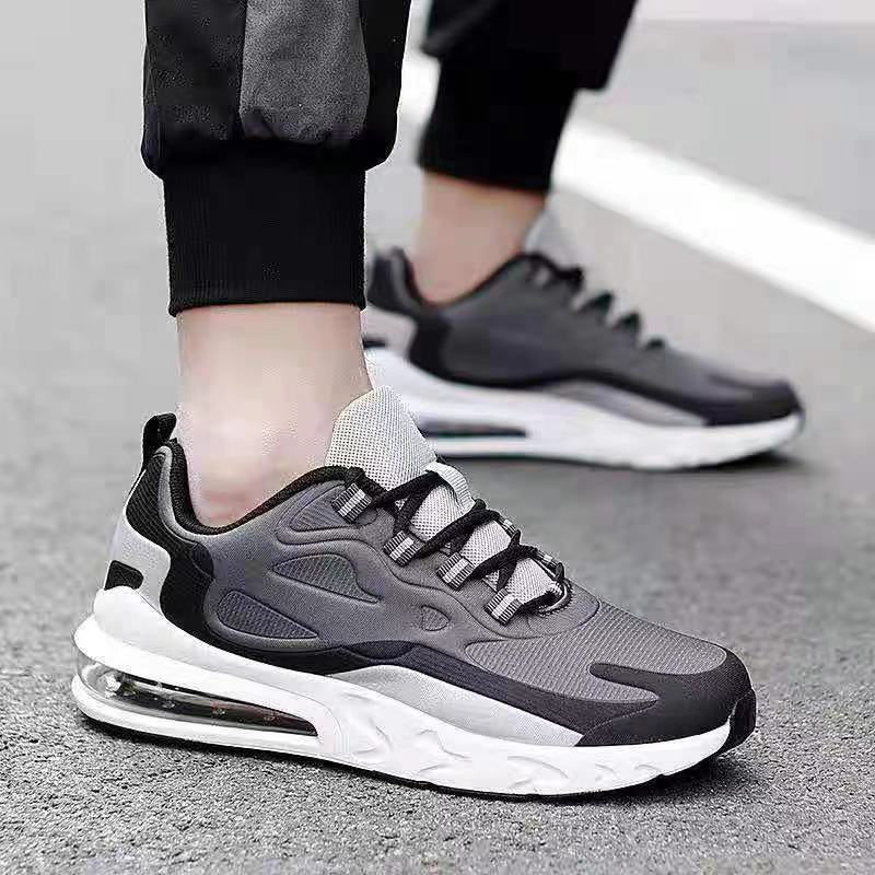 Gray and black athletic shoes worn by a person on a gray pavement.