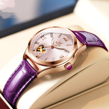 Luxury watch with purple strap and rose gold case on a beige surface