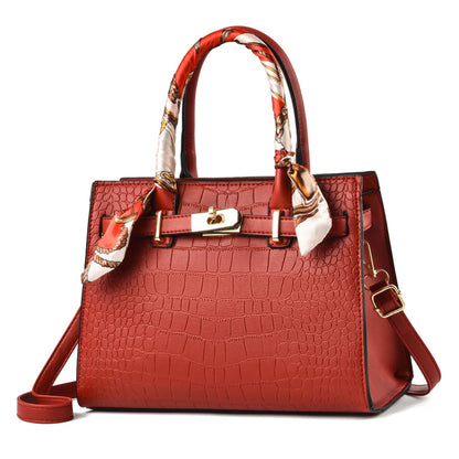 Red handbag with a patterned scarf on a white background