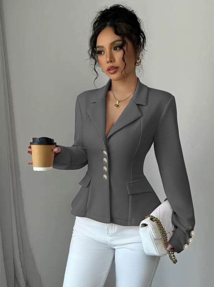 Woman in a gray blazer holding a coffee cup against a plain background