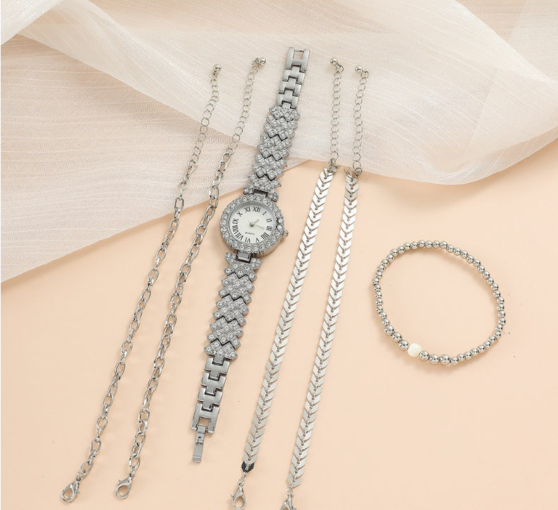 Silver watch and bracelets on a person's arm with a light background