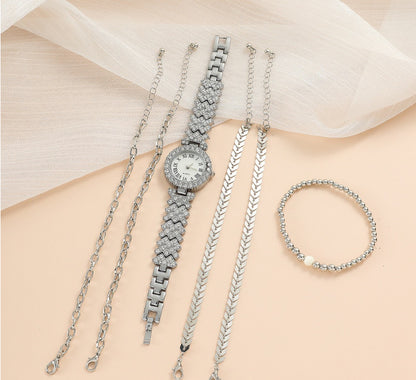 Silver watch and bracelets on a person's arm with a light background