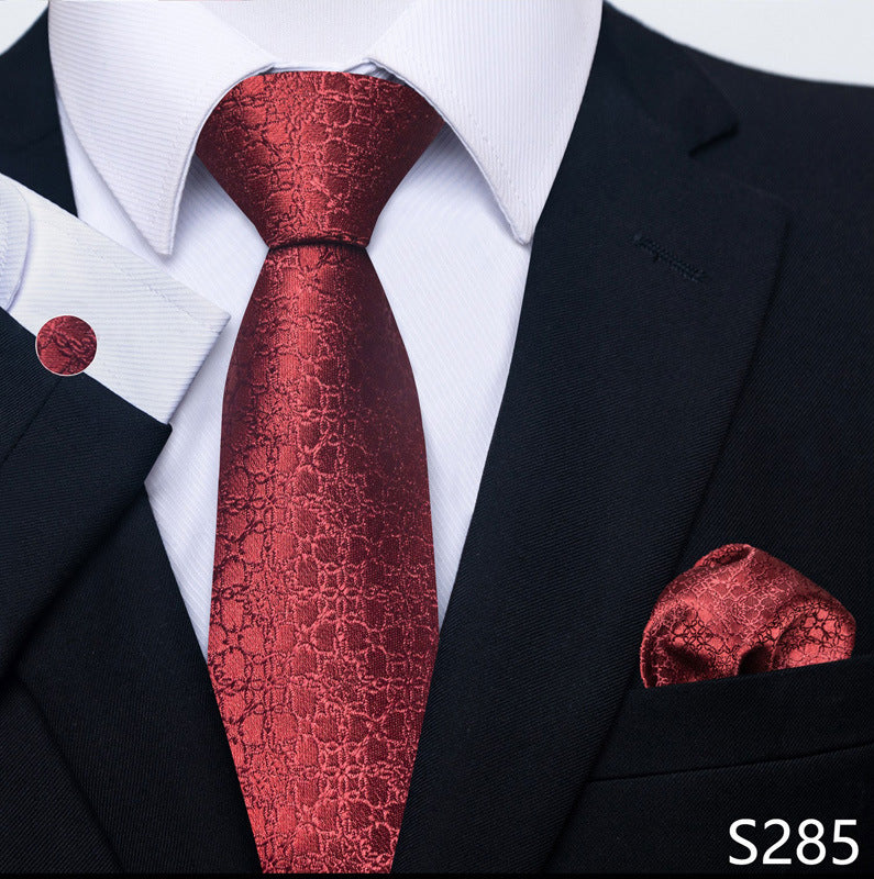Red patterned tie and pocket square set with a black suit and white shirt.