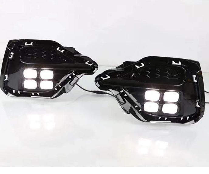 Pair of black motorcycle foot pegs with LED lights on a white background
