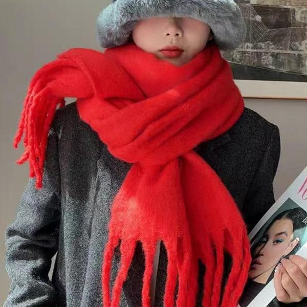 Person wearing a red scarf and gray hat with a magazine in the background
