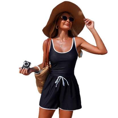 Woman in black tank top and shorts with a wide-brimmed hat on a white background