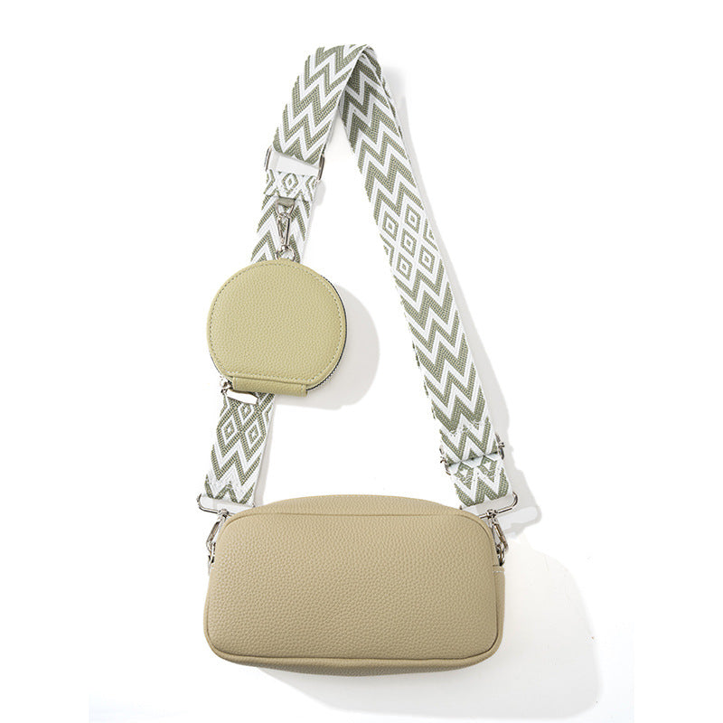Beige crossbody bag with a patterned strap on a white background
