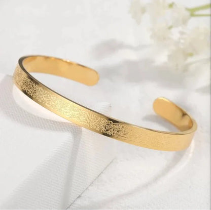Gold-tone wide cuff bangle with engraved Islamic script, open oval shape