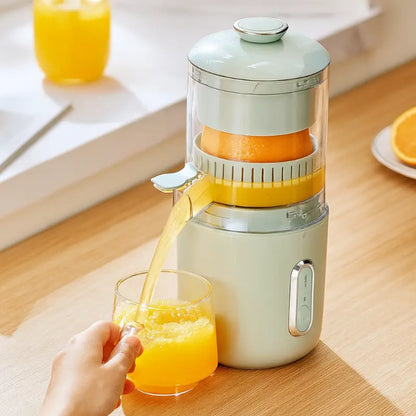 White portable electric juicer with glass cup and freshly poured orange juice