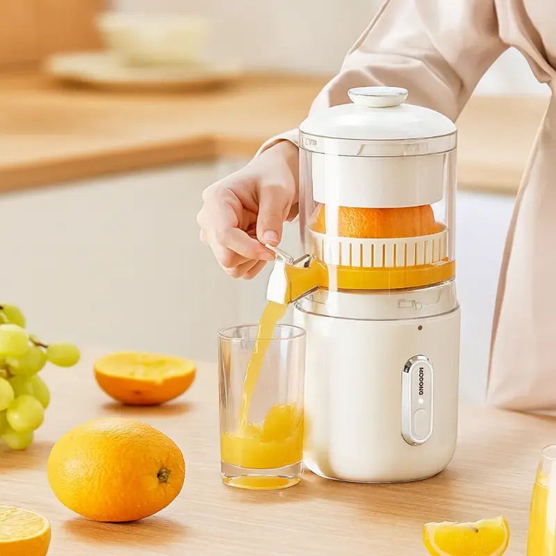 White portable electric juicer with pitcher spout and orange juice in glass