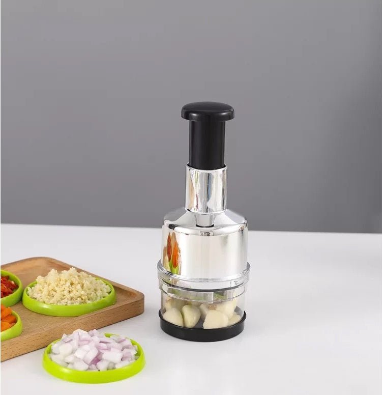 Manual press chopper on countertop with ingredients prepped on cutting board