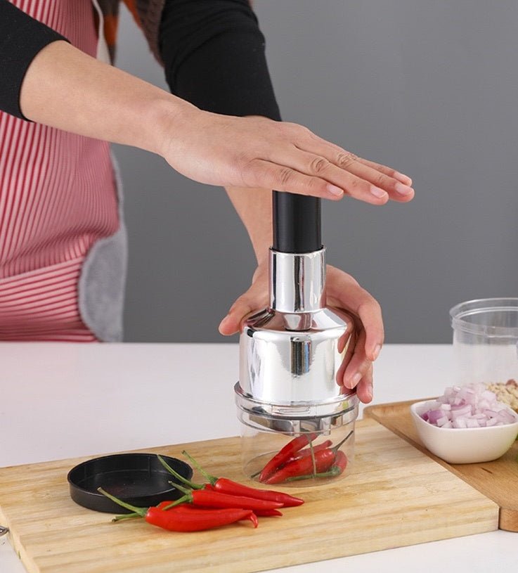 Manual press chopper in hand with stainless-steel body and clear chopper cup